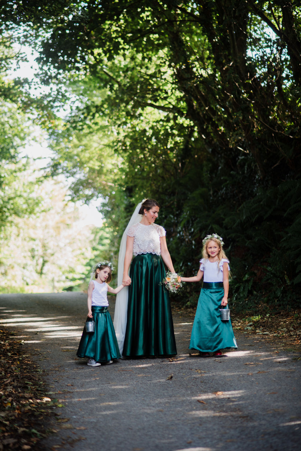 Rustic barn wedding photography by Liberty Pearl Photo & Film Collective. Bride and children walk through woods.