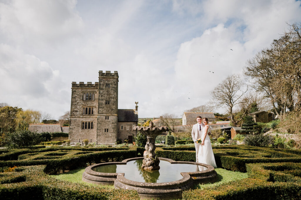 A newlywed couple walking through the gardens of Pengersick Castle in Cornwall