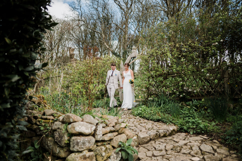 A newlywed couple stood side by side about to start walking through the gardens of Pengersick Castle in Cornwall